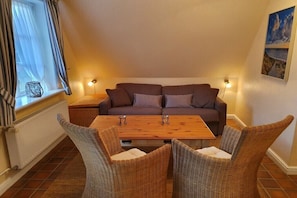 Ein gemütlicher Wohnbereich mit einer Couch, einem Holztisch und Korbstühlen.