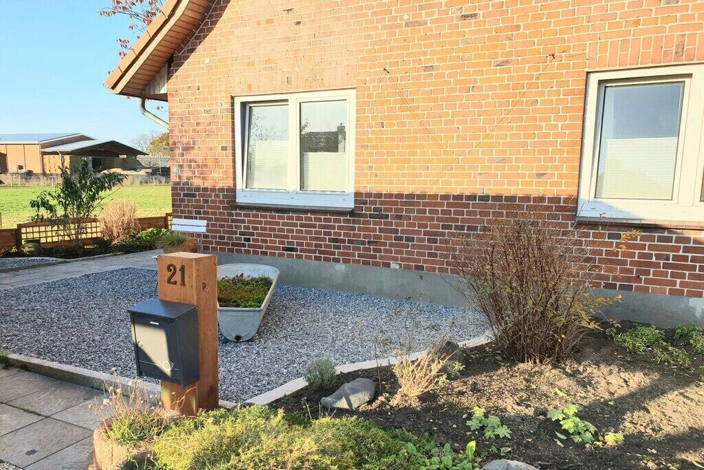 A brick building with a mailbox marked '21' and a small garden area with gravel and plants.