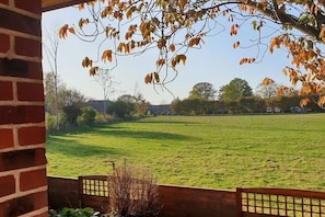 A view from a brick wall to a grassy field with trees and a fence in the distance. - Holiday apartment with 1 bedroom (Niendorf  a.Fehmarn)