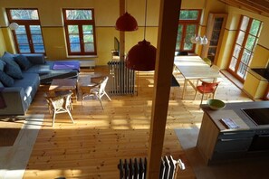 Zona d'estar àmplia amb sofà, cadires, taula de dinar i zona de cuina.