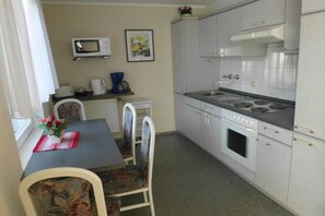Une cuisine compacte équipée d’un four à micro-ondes, d’une cuisinière et d’un coin repas avec une table et des chaises.