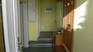 A hallway with a wooden door, a small staircase, and a wall-mounted picture. - in Putbus - Kummer family (Putbus)