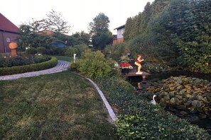 A garden with a curved pathway, a pond with rocks, and a statue. - 1 Hein Garrn Fruit Farm (mittelnkirchen)