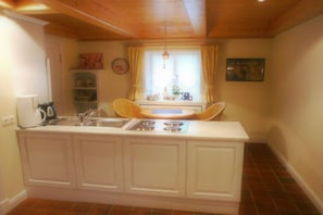 Een kleine keuken met een inbouw kookeiland, een spoelbak en een fornuis.