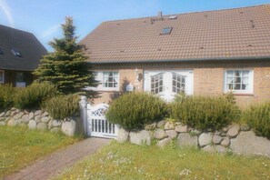 A two-story brick house with a tiled roof, a white gate, and a small tree in the front yard. - Holiday apartment with 2 bedrooms (List auf Sylt)