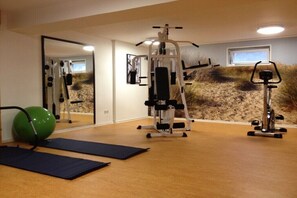 A gym with exercise equipment, a green exercise ball, and mats on the floor. - Holiday apartment with 2 bedrooms (Norderney)
