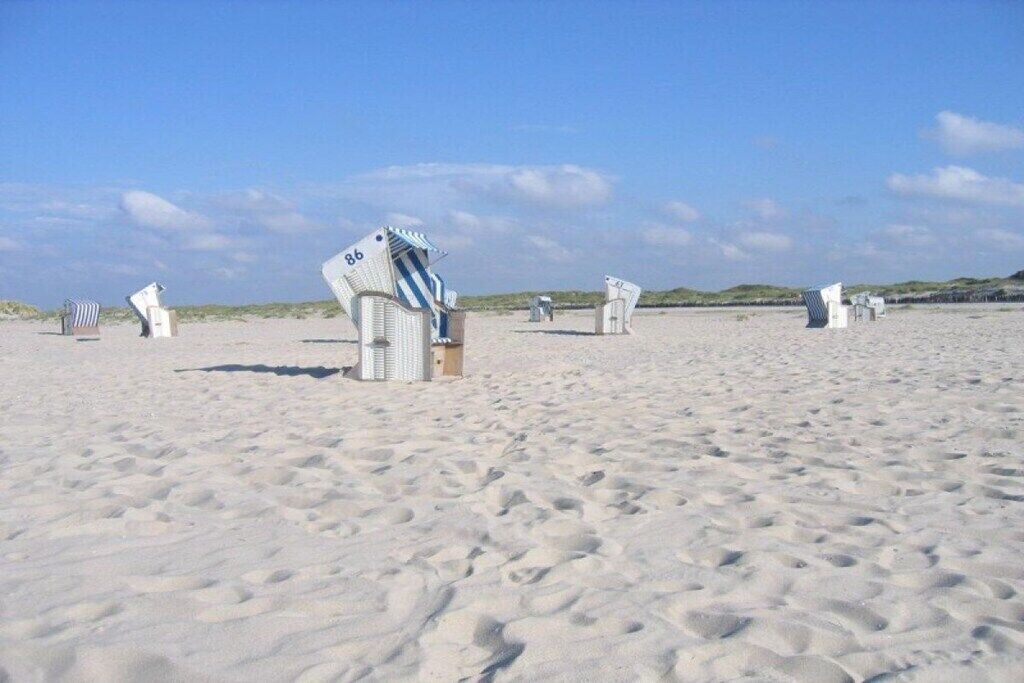 A sandy beach with several white structures, possibly beach huts, scattered across the sand.