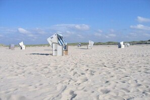 Ein sandiger Strand mit mehreren weißen Gebilden, vermutlich Strandhütten, verteilt im Sand.