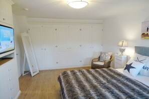 A bedroom with a bed, a television, a wardrobe, a chair, and a nightstand. - Holiday home in List with sauna and Wi-Fi (List)