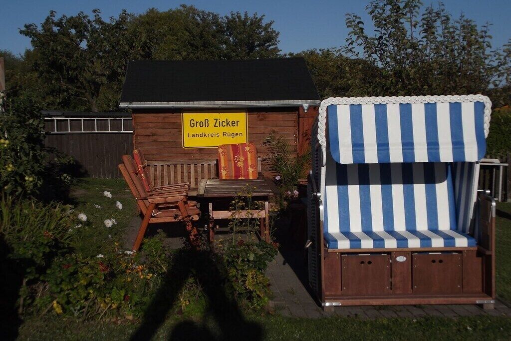 A wooden structure with a sign reading 'Groß Zicker Landkreis Rügen,' a wooden bench, and a striped canopy.