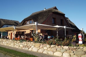 A traditional building with a thatched roof, outdoor seating area, and stone wall. - Holiday apartment with 2 bedrooms (Groß Zicker)