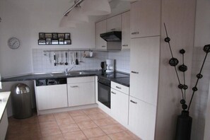 A kitchen with white cabinets, a black countertop, a coffee maker, and a trash can. - Holiday apartment with 1 bedroom (Büsumer Deichhausen)
