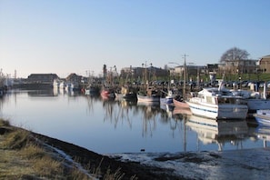 Un port de plaisance avec des bateaux amarrés, une étendue d’eau calme et des bâtiments en arrière-plan.