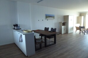 A modern kitchen with a dining area, a flat-screen TV, and a wardrobe. - Holiday apartment with 2 bedrooms (Wilhelmshaven)