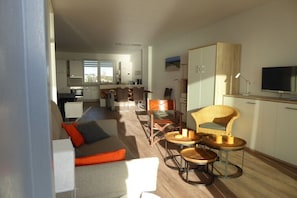 A modern living room with a sofa, chairs, and a dining area with a table and chairs. - Holiday apartment with 2 bedrooms (Wilhelmshaven)