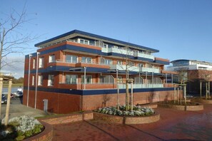 A multi-story building with a flat roof, large windows, and a brick facade. - Holiday apartment with 2 bedrooms (Wilhelmshaven)