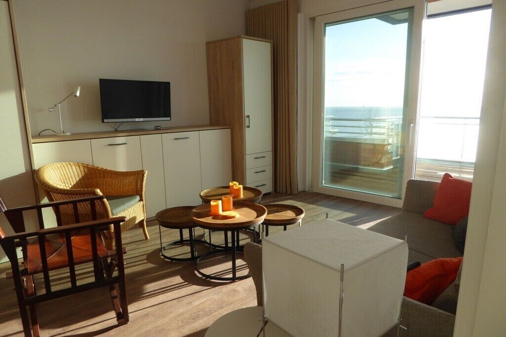 A modern hotel room with a television, seating area, and a view of the sea.