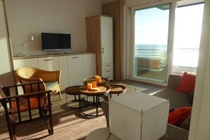 A modern hotel room with a television, seating area, and a view of the sea. - Holiday apartment with 2 bedrooms (Wilhelmshaven)