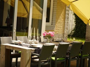 An outdoor dining area with wicker chairs and a table set for a meal, featuring candles and flowers. - Villa in RZ Kamperland With Swimming Pool (Kamperland)