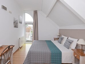 A bedroom with a bed, a desk, a chair, a nightstand, and a window with curtains. - Villa in RZ Kamperland With Swimming Pool (Kamperland)