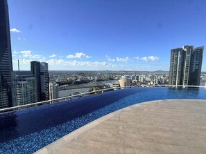 A rooftop infinity pool with a cityscape view, surrounded by modern high-rise buildings. - Metropolitan Luxe | Balcony with Skyline Views (Brisbane City)