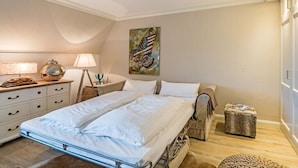 Ein Schlafzimmer mit einem Bett, Nachttischen, einer Lampe, einem Gemälde und einem Fenster.