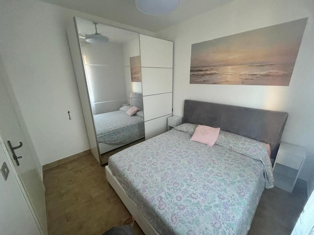 A bedroom with a bed, a mirror, a painting, and a wardrobe.