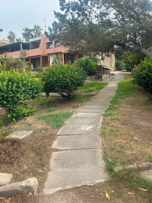 A pathway leading to a building with a stone facade and a covered area with a person visible. - Apartment in Stintino with terrace and Asinara view (Stintino)