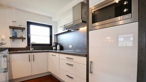 Eine moderne Küche mit weißen Schränken, Edelstahlgeräten und einem Fenster über der Spüle.