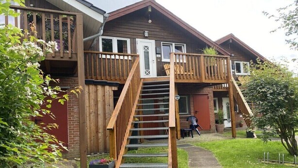 A two-story wooden house with a balcony, a staircase, and a small garden area. - Holiday apartment in Holnis with Wi-Fi (Holnis)