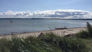 A beach with calm water, a boat on the shore, and people in the water. - Holiday apartment in Holnis with Wi-Fi (Holnis)