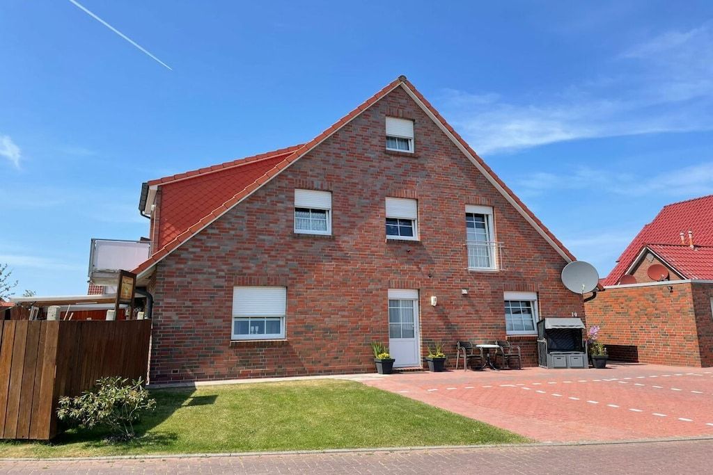 A brick house with a red roof, a satellite dish, and a small garden.