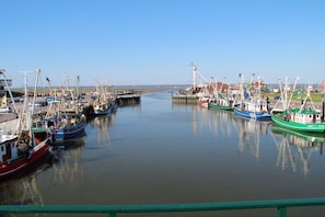 A marina with multiple boats docked, a clear sky, and a calm water surface. - Sailor House Semi-detached (Dornumersiel)