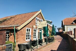Ein traditionelles Backsteingebäude mit einem Schild für 'Restaurant & Pub' und Außenbereich mit Sonnenschirmen.