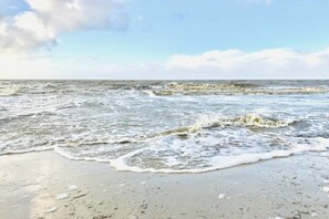 A beach with waves approaching the shore. - Holiday apartment with 1 bedroom (Neuharlingersiel)