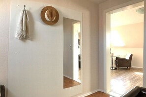 A room with a mirror, a hat, and a towel on the wall. - Holiday apartment with 1 bedroom (Neuharlingersiel)