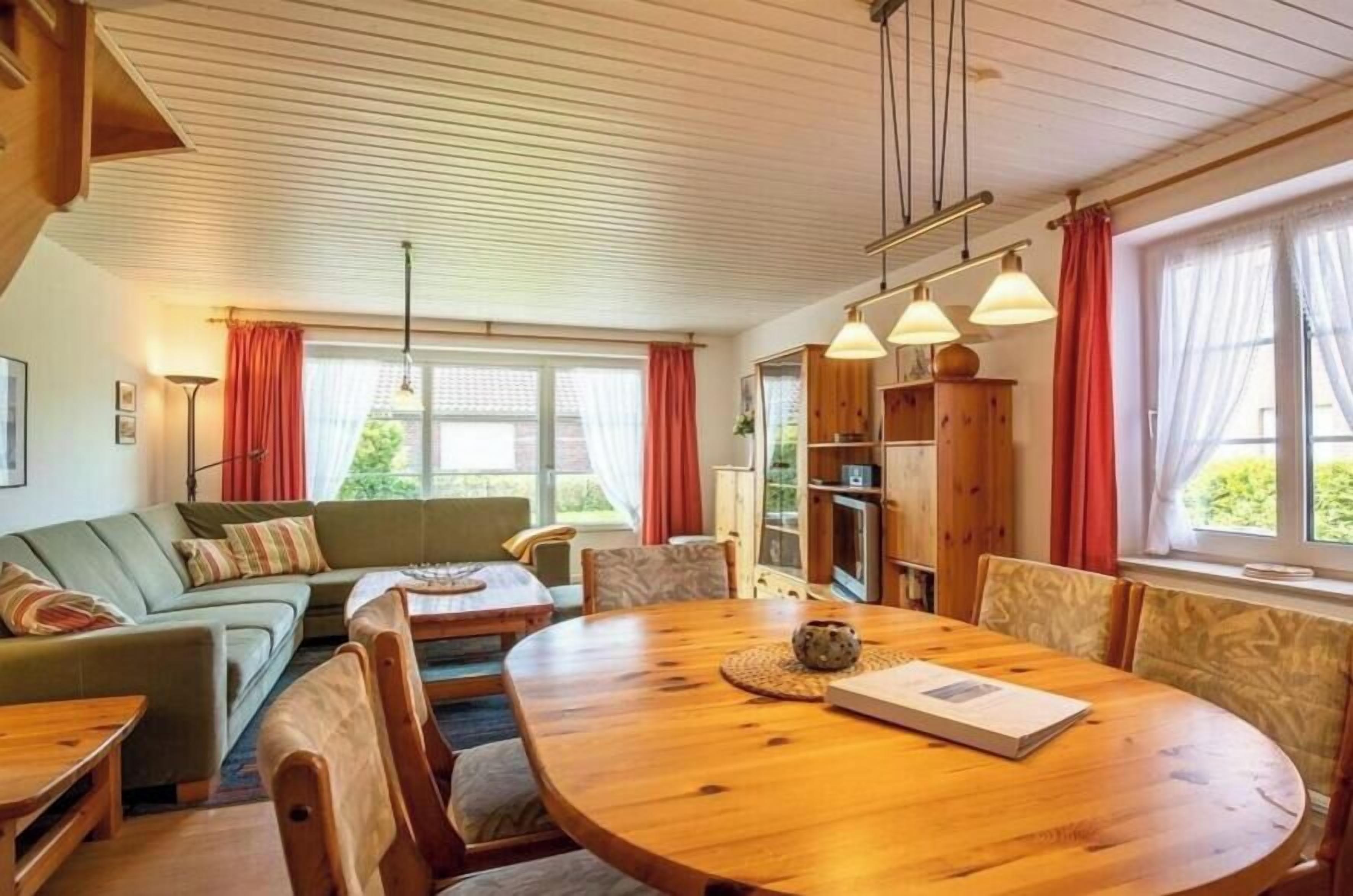A cozy living room with a wooden dining table, a sofa, and a bookshelf.