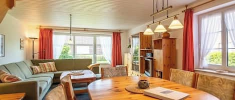 A cozy living room with a wooden dining table, a sofa, and a bookshelf.