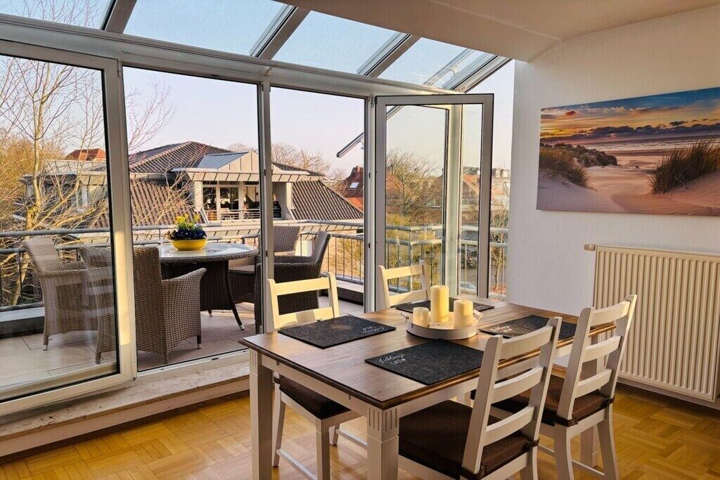 A dining area with a table and chairs, a glass door leading outside, and a painting on the wall.