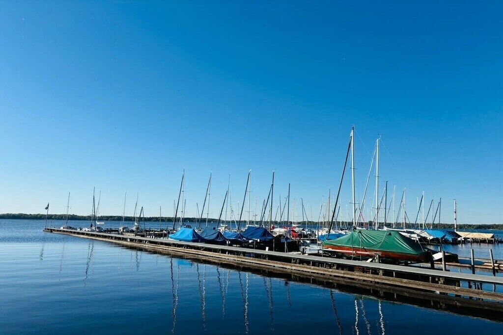 Un port de plaisance où de nombreux voiliers sont amarrés le long d’une jetée en bois.