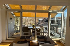 Ein Essbereich mit einem Tisch für zwei Personen, einer Glastrennwand und Blick auf die Terrass.