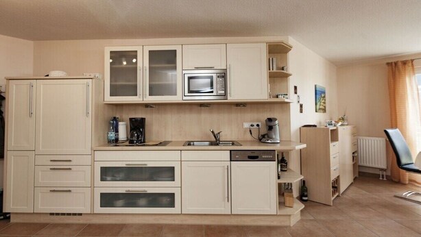 A compact kitchen with a microwave, coffee maker, and a dishwasher. - Holiday apartment in Sylt with swimming pool (Sylt)