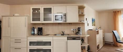 Cocina compacta equipada con microondas, cafetera y lavavajillas.