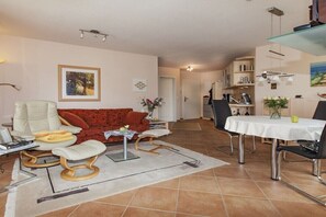 Een woonkamer met een bank, een eettafel met stoelen en een keuken op de achtergrond.