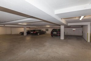 A parking garage with concrete floors and white walls, featuring several parked cars. - Holiday apartment in Sylt with swimming pool (Sylt)