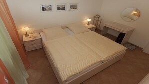 A bedroom with a bed, bedside tables, a mirror, and framed pictures on the wall. - Holiday apartment in Sylt with swimming pool (Sylt)