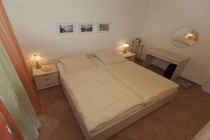 Een slaapkamer met een bed, nachtkastjes, een spiegel en lijstjes met foto's aan de muur.