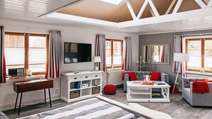 A spacious living room with a high ceiling, large windows, a flat-screen TV, and a fireplace. - Holiday home with 1 bedroom (Grödersby)