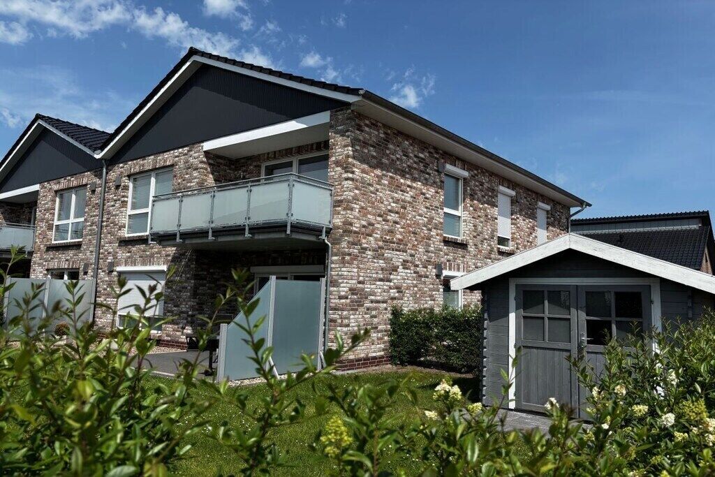 Une maison à deux étages avec une façade en pierre, un balcon et un garage.
