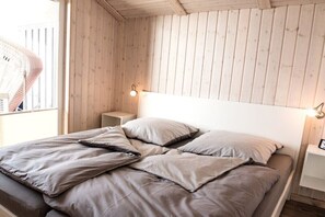 A bed with a headboard, pillows, and a bedside table with a lamp. - Holiday home in Wesselburenerkoog with Wi-Fi (Wesselburenerkoog)